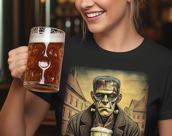 May include: A black short-sleeved t-shirt featuring a graphic print of a green-skinned monster wearing a dark coat and holding a glass beer mug. The illustration shows the character standing in a town square with buildings in the background.