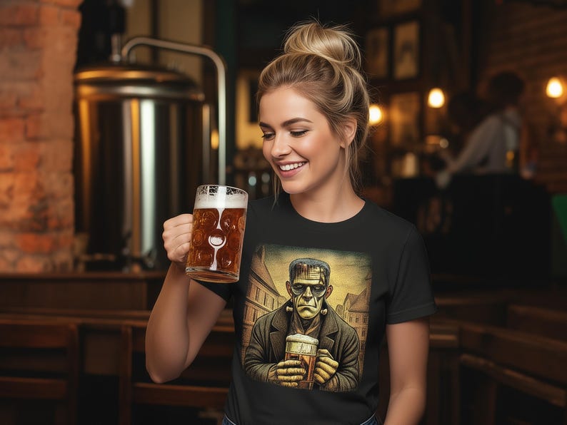 May include: A black short-sleeved t-shirt featuring a graphic print of a green-skinned monster wearing a dark coat and holding a glass beer mug. The illustration shows the character standing in a town square with buildings in the background.