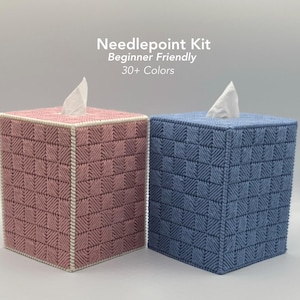 May include: Two square tissue box covers, one pink and one blue, with a woven needlepoint design. The covers have white trim and a tissue peeking out of the top. Text on the image reads "Needlepoint Kit, Beginner Friendly, 30+ Colors."