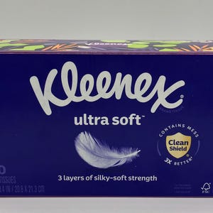 Puede incluir: Una caja rectangular de pa&ntilde;uelos Kleenex Ultra Soft en color morado oscuro. El frente presenta el nombre de la marca, un gr&aacute;fico de pluma blanca y texto que indica 120 pa&ntilde;uelos de 3 capas, 20,8 x 21,3 cm y un logo Clean Shield de protecci&oacute;n.