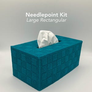 May include: A teal needlepoint tissue box with a large rectangular shape. The box has a woven pattern and a rectangular opening at the top. The text "Needlepoint Kit Large Rectangular" is displayed on the image.