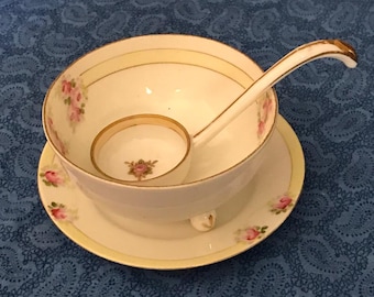 May include: A white porcelain soup bowl with a gold rim and floral design, paired with a matching ladle. The bowl has a pedestal base and sits on a matching saucer with a gold rim and floral design.