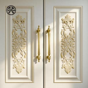 Può includere: Primo piano di una doppia porta bianca con maniglie dorate e pannelli decorativi con rilievi floreali. Le maniglie sono lunghe e cilindriche, con terminali decorativi. I pannelli in rilievo presentano disegni floreali simmetrici.