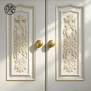 May include: Close-up of a white cabinet door with ornate, gold-colored floral relief carvings. The door features two gold-toned, octagonal knobs. The brand logo "Orlande" is visible in the upper left corner.