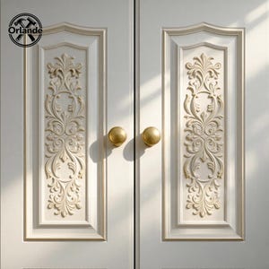 Puede incluir: Primer plano de un par de puertas de armario blancas con intrincados tallados florales en relieve y detalles dorados. Cada puerta tiene un pomo dorado. El logotipo "Orlande" es visible.