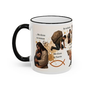 Puede incluir: Taza de cerámica blanca con asa y borde negros. La taza presenta ilustraciones de figuras y texto en español, incluyendo "Me dices no temas" y "Me dices se fuerte". También hay un corazón y un símbolo de pez.