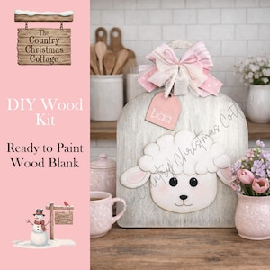 May include: DIY wood kit featuring a sheep design. The wooden blank is ready to paint and includes a pink tag that says "baa". The kit is from "The Country Christmas Cottage". A pink and white bow is attached to the top.
