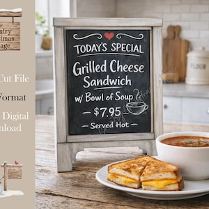 May include: A chalkboard sign with the text "TODAY'S SPECIAL Grilled Cheese Sandwich w/ Bowl of Soup - $7.95 - Served Hot." A plate with a grilled cheese sandwich and a bowl of soup are in front of the sign.