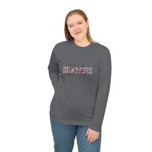 May include: A long-sleeved, dark gray shirt with the word "Dunmore" printed on the front in a combination of red script and gray block letters. The shirt is made of a lightweight material and is being worn by a person.