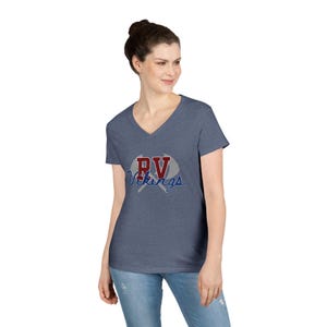 May include: A blue V-neck t-shirt featuring the text "PV Vikings" in red and blue. The text is above a pair of crossed gray objects. The shirt is made of a soft material. The t-shirt is a heathered blue.