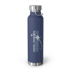 Op de afbeelding: Een marineblauwe geïsoleerde waterfles met een zilveren deksel en handvat. De fles heeft het woord "COMETS" in witte en blauwe letters met een ster- en gebogen lijnontwerp. De fles is ongeveer 25 cm hoog.