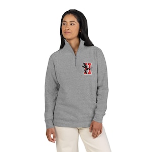 May include: A gray quarter-zip sweatshirt with a small embroidered design on the upper left chest. The design features a black and red insect with the letter "H" in the background. The sweatshirt has a high collar and a silver zipper.