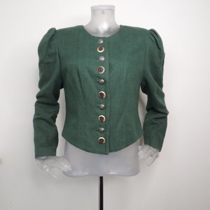 May include: A forest green long-sleeved jacket featuring a round neckline, structured puff shoulders, and a front button closure. The jacket is secured with a vertical row of alternating silver-toned metal buttons and brown circular buttons.