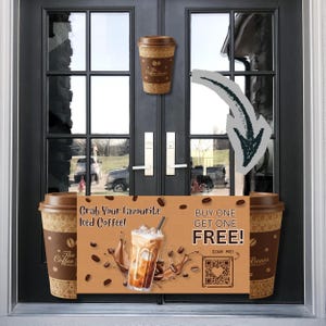 May include: A brown and tan coffee cup with the text "The Coffee Beans" is displayed on a black door. A sign promoting iced coffee with the text "Grab Your Favourite Iced Coffee!" and "BUY ONE GET ONE FREE!" is also visible.