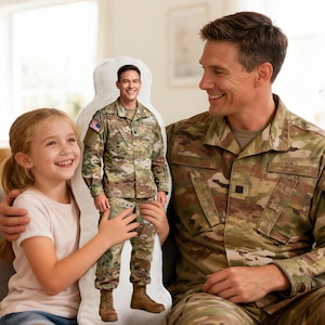 May include: A custom-shaped pillow featuring a full-body image of a person in a military uniform. The pillow is held by a young girl and a man in a matching uniform, both smiling. The background shows a living room setting.