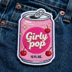 May include: Pink embroidered patch in the shape of a soda can with the words "Girly Pop" in white script. The patch features cherries and stars, and the bottom reads "12 FL OZ."