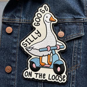 May include: Embroidered patch featuring a white goose riding a light blue scooter. The patch has the words "SILLY GOOSE ON THE LOOSE" in black lettering. The goose has an orange beak and feet, and the scooter has pink handlebars and black wheels.