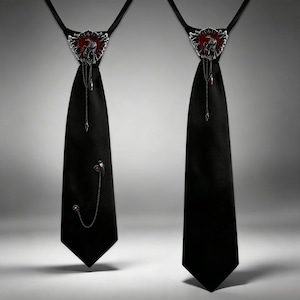 Peut inclure: Deux cravates noires ornées d'un emblème en métal argenté au niveau du nœud, avec un fond rouge et un motif d'oiseau. Les cravates sont décorées de fines chaînes argentées et de petits breloques, l'une ayant une chaîne et un oiseau en plus.