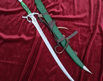 Pode incluir: Uma espada de fantasia com uma lâmina prateada e uma empunhadura verde com entalhes decorativos. A espada é acompanhada por uma bainha verde com correias de couro castanho. A ponta da bainha é prateada.