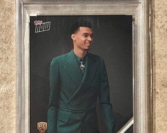 May include: A 2023 Topps Now trading card featuring Victor Wembanyama in a green suit. The card is graded GEM MT 10 by PSA and includes the text "DRAFT" and "SELECTED WITH 1ST OVERALL DRAFT PICK".