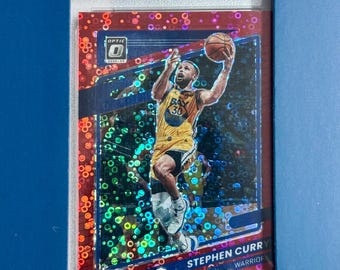 May include: A 2021 Donruss Optic Stephen Curry Fast Break Red basketball trading card graded PSA Gem Mint 10. The card features Curry in a yellow jersey mid-air with a basketball, set against a red holographic background with circular patterns.