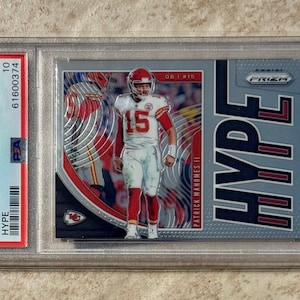 Può includere: Una carta collezionabile di football di Patrick Mahomes II della serie Panini Prizm 2019. La carta presenta Mahomes con la sua uniforme dei Chiefs, con la parola "HYPE". La carta è valutata GEM MT 10 da PSA.