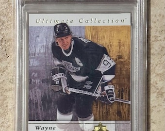 May include: A Wayne Gretzky hockey card from the 2011 Ultimate Collection series. The card features Gretzky in his Kings uniform. The card is graded GEM MT 10 by PSA, with serial number 106745185. The card is numbered 286/399.