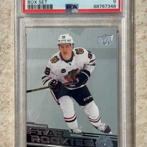 May include: A graded Connor Bedard hockey card from the 2023 UD Star Rookies Box Set. The card features a player in a Chicago Blackhawks uniform. The card is graded MINT 9 by PSA and is encased in a protective holder.