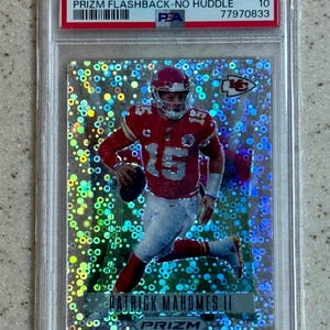 Könnte beinhalten: Eine 2022 Prizm Patrick Mahomes II Prizm Flashback-No Huddle Sammelkarte, bewertet mit PSA 10 Gem Mt. Die Karte zeigt einen holografischen silbernen Hintergrund mit kreisförmigem Muster und das Bild eines Footballspielers in rot-weißem Trikot.