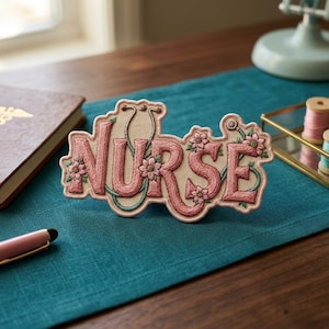 May include: Embroidered patch with the word "NURSE" in pink script, adorned with floral accents and a stethoscope design. The patch is set against a neutral background, with a teal table runner and other decorative items.