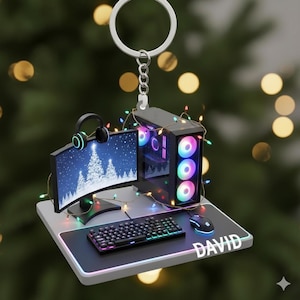 May include: A gaming PC ornament with a keyboard, mouse, monitor, and headphones. The monitor displays a winter scene. The name "DAVID" is printed on the mousepad. The ornament is decorated with colorful lights and a silver keychain.