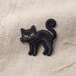 May include: A black cat embroidered patch featuring a curled tail and bright yellow eyes. The cat is depicted in a standing position with its head turned toward the left, showcasing detailed black thread work and a small pink nose detail.