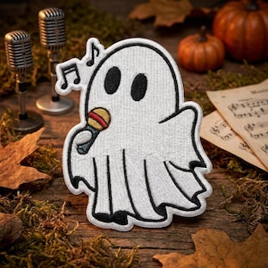 May include: An embroidered patch featuring a white ghost with black oval eyes, holding a small microphone with a red and yellow striped head, accompanied by two black musical notes floating above its head, outlined in thick black thread.