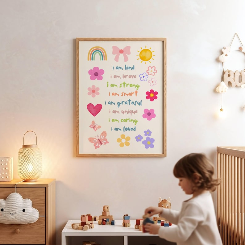 May include: A framed wall art print featuring a cream background with colorful illustrations of a rainbow, bow, sun, heart, butterflies, and flowers. The text reads: i am kind, i am brave, i am strong, i am smart, i am grateful, i am unique, i am caring, i am loved.