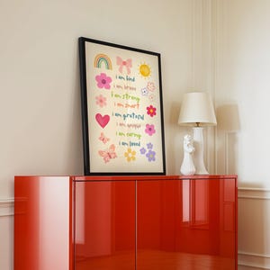 This vibrant digital download features a collection of kids' daily affirmations designed to inspire confidence. The artwork includes uplifting phrases such as "I am kind," "I am brave," and "I am loved," beautifully surrounded by colorful illustrations of flowers, a sun, a rainbow, and butterflies. Perfect for decorating a child's room, playroom, or nursery, creating an uplifting environment that encourages kids to embrace a positive mindset and boosts their self-esteem.
