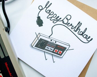May include: A white card with a black and white illustration of a Nintendo controller with a cord that spells out "Happy Birthday".