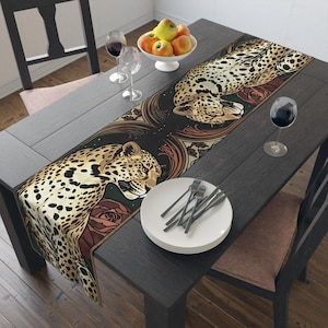 Peut inclure: Un chemin de table rectangulaire présentant un motif répétitif de deux léopards au pelage tacheté d'or et de noir, sur un fond sombre orné de roses brunes stylisées et d'éléments décoratifs complexes en forme de volutes.