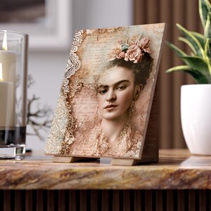 May include: A rectangular tabletop plaque featuring a sepia-toned portrait of a person with flowers in their hair. The artwork includes intricate lace patterns, script text overlays, and decorative gold-colored filigree elements on a textured background.