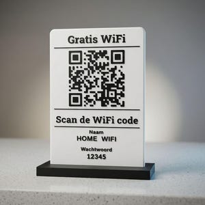 Può includere: Un cartello rettangolare bianco con testo nero e un codice QR, montato su una base nera. Il cartello recita "Gratis WiFi" in alto, seguito da un codice QR e "Scan de WiFi code". Sotto, mostra "HOME WIFI" e "12345".
