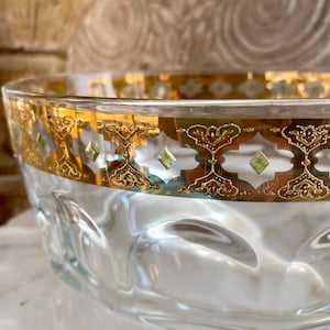May include: A clear glass bowl with a gold and green patterned rim. The bowl has a textured, bubbled surface.