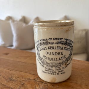 May include: An antique James Keiller & Son's Dundee Marmalade jar. The off-white ceramic jar features a black and white label with text and a decorative border. The jar is marked "Contents 1 lb. net."