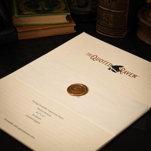 May include: Cream-colored paper with the text "THE QUOTED RAVEN" and a raven illustration. A gold wax seal is affixed to the paper. The paper is labeled "Vintage Erasable Typewriter Paper" and lists dimensions and sheet count.