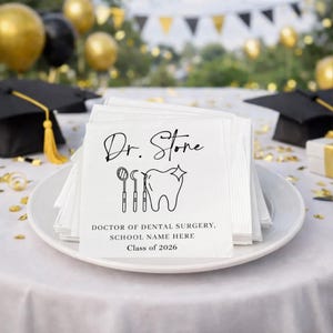 May include: White paper napkins stacked on a white plate, featuring a dental-themed design. The napkins are printed with the words "Dr. Stone," a tooth graphic, and the text "Doctor of Dental Surgery, School Name Here, Class of 2026."