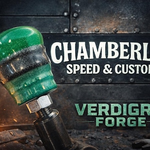 May include: A custom shift knob with a green and black marbled design. The knob is attached to a metal shaft with a hex nut. The background features the text "CHAMBERLIN SPEED & CUSTOM" and "VERDIGRIS FORGE" on a textured metal surface.