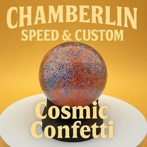 May include: A decorative sphere with a cosmic confetti design, featuring orange, blue, and silver glitter. The sphere is displayed on a white and black stand, with the text "Cosmic Confetti" below. The background is a solid yellow.