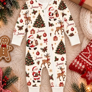 May include: A cream-colored long-sleeve romper with a front zipper closure and white ribbed cuffs. The fabric features a repeating Christmas pattern of Santa Claus, reindeer, decorated pine trees, gift boxes, and the name James in red script.