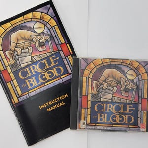 May include: A vintage "Circle of Blood" PC game set. The instruction manual and CD-ROM case feature a stained-glass style design with a gargoyle. The game title is in gold lettering. The CD-ROM case is black.