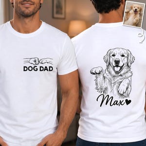 May include: White t-shirts with black graphics. One shirt has the text "DOG DAD" above a fist bump design. The other shirt features a Golden Retriever illustration with the name "Max" and a heart.