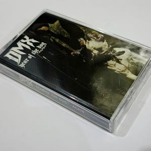 May include: A clear cassette tape case featuring the album art for DMX's "Year of the Dog... Again." The cover art is dark with a dog and a person in the image. The album title and artist name are visible.