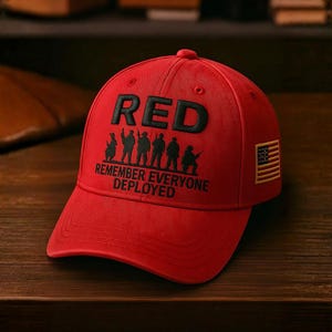 Könnte beinhalten: Rote Baseballkappe mit dem Wort "RED" in großen, schwarzen Buchstaben. Darunter Silhouetten von Soldaten und der Text "REMEMBER EVERYONE DEPLOYED". Ein amerikanischer Flaggenaufnäher befindet sich an der Seite.